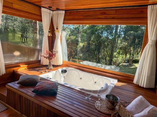a bath tub in a room with a large window at Villa Vida Cabanas in São Joaquim