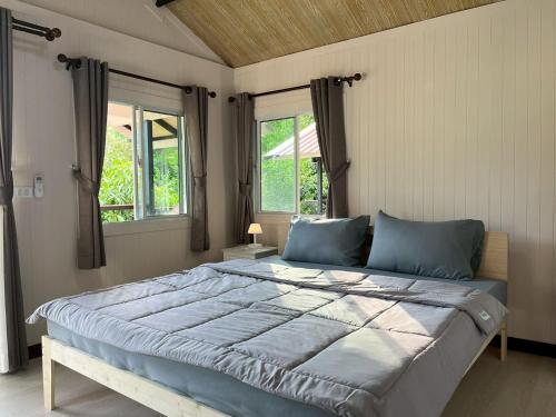 a large bed in a room with two windows at Wildnest House in Ko Yao Noi