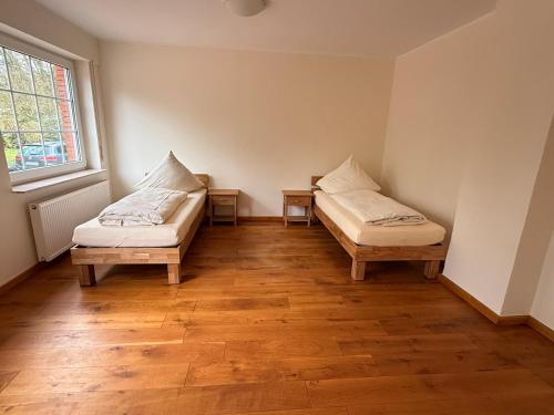 two beds in a room with wooden floors and a window at Haus an der Hase in Bramsche