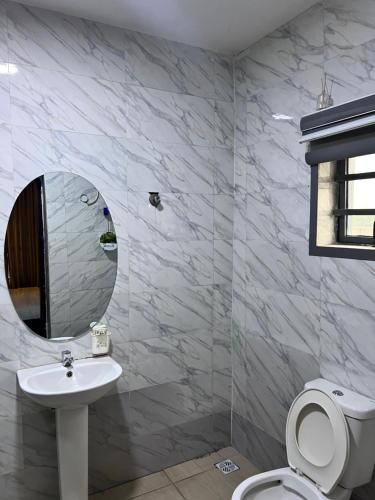 a white bathroom with a sink and a mirror at Executive 2-Bedroom Apartment in Ikeja