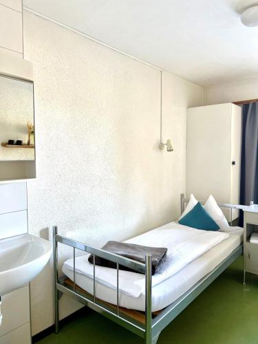 a small bedroom with a bed and a sink at Gruppenhaus Frutigresort in Frutigen