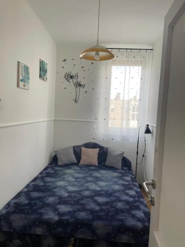 a bedroom with a blue bed in a room with a window at Kolor House Apartman in Kazincbarcika