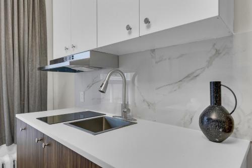 a white kitchen with a sink and a vase at Maison Paris- Quartier des Spectacles in Montreal