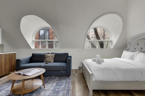 a bedroom with a bed and a couch and two arched windows at Maison Paris- Quartier des Spectacles in Montreal