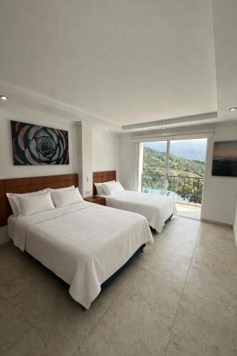 two beds in a bedroom with a large window at Hotel Cabaleón in Tena