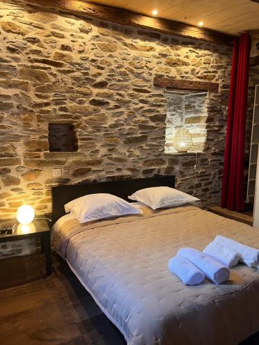 a bedroom with a large bed in a stone wall at la grange d'Eugenie in Estaing