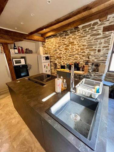 a kitchen with a sink and a stone wall at la grange d'Eugenie in Estaing