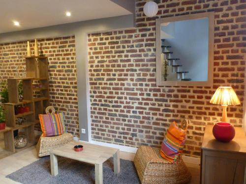 a living room with a brick wall and two chairs and a table at spéculoos et chicorée in Villeneuve d'Ascq