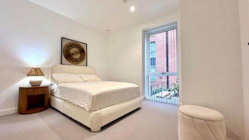 a white bedroom with a bed and a window at Sunshine Place Brent Cross in London