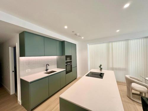 a kitchen with green cabinets and a sink at Sunshine Place Brent Cross in London