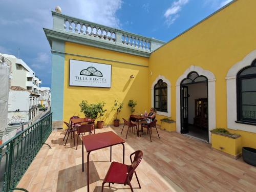 a yellow building with tables and chairs on a deck at Tilia Hostel in Faro