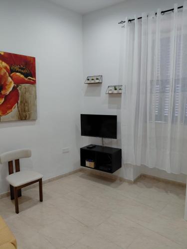 a living room with a television and a chair at Charming Ground-floor Maisonette in Birgu