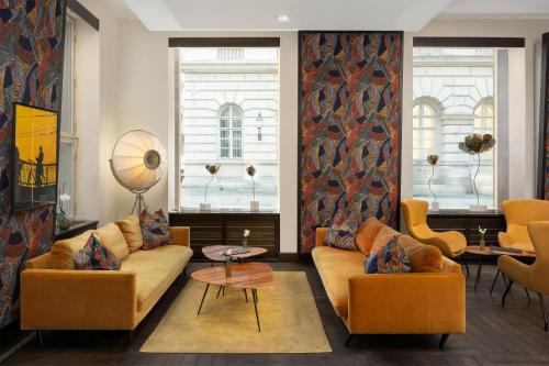 a living room with a couch and chairs and windows at Radisson Blu Style Hotel, Vienna in Vienna