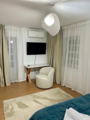 a bedroom with a bed and a tv and a chair at Aquae Flaviae Urban Stay - Duplex in Chaves