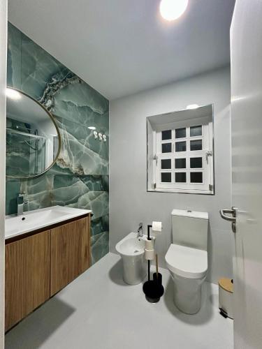a bathroom with a toilet and a sink and a window at Aquae Flaviae Urban Stay - Duplex in Chaves