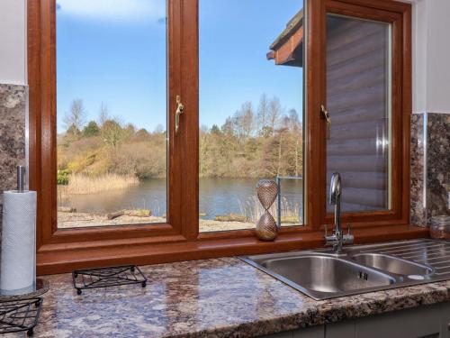 a kitchen sink with a window overlooking a lake at Star Carr Lakes in Great Driffield