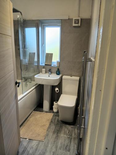 a bathroom with a toilet and a sink and a tub at Dale combe in Middleton