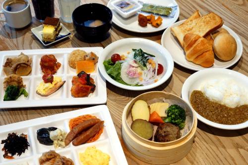 a wooden table with plates of food on it at Rembrandt Style Yokohama Sakuragicho in Yokohama
