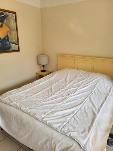 a white bed in a bedroom with a painting on the wall at Heliotel Marine plages piscines tennis terrasse jardin in Saint-Laurent-du-Var