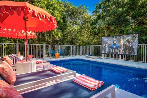 a pool with chairs and an umbrella and a tv at NEW!The HideawayPoolPickleballPutt-PuttKayaks! in Marathon