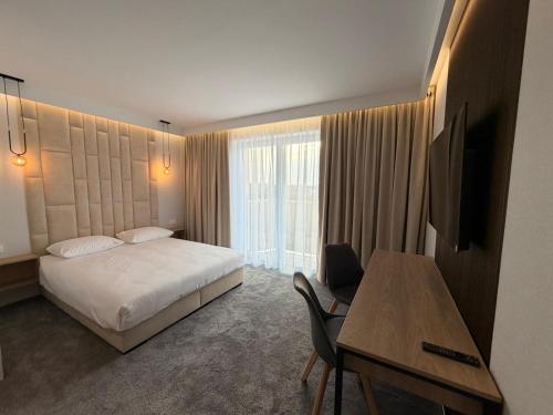 a hotel room with a bed and a desk and a table at Baltic Waves Ex LAZUR in Gąski