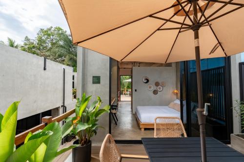 an outdoor patio with a bed and an umbrella at The Sandhaus - Boutique Design Villa with 8 Suites in Jacó