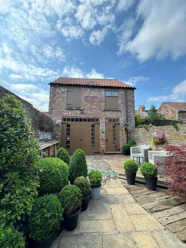 a brick house with a patio and some bushes at The Old Hayloft Beverley Town Centre in Beverley