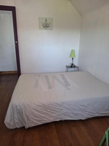 a bedroom with a white bed and a table with a lamp at Chambre dans village tranquille in Saint-Laurent-de-la-Plaine
