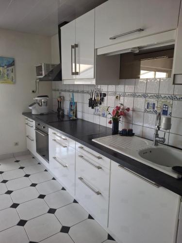a kitchen with white cabinets and a sink at Chambre dans village tranquille in Saint-Laurent-de-la-Plaine