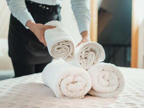 a person stacking towels on a bed at Wisdom Park Caravan Camp Pattaya in Ban Khao Mai Kaeo