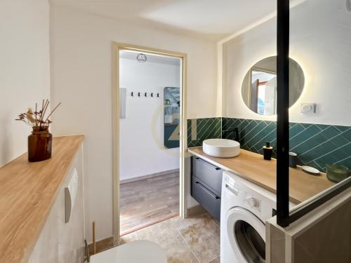 a bathroom with a sink and a washing machine at Duplex T2 - Madonna di a Sarra in Calvi