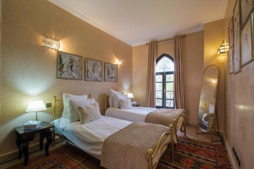 a hotel room with two beds and a window at Riad Malak Palmeraie in Marrakesh