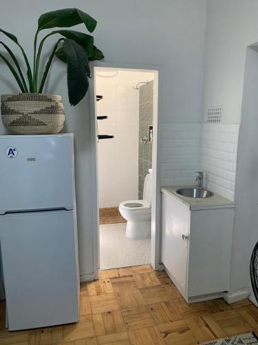 a bathroom with a sink and a toilet and a refrigerator at Just a Bed parking on street in Stellenbosch
