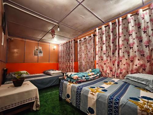 a room with three beds and a table and curtains at White Sea Homestay, Dowhill Kurseong in Kurseong