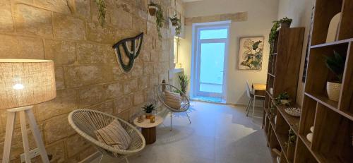 a room with two chairs and a stone wall at The Alley Suites in Gudja