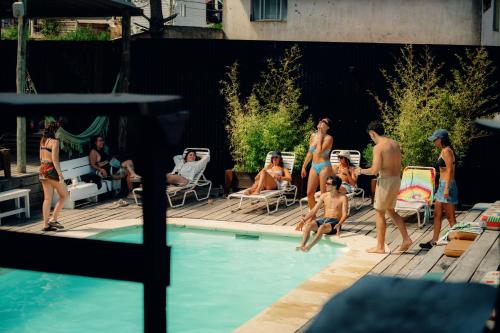 a group of people standing around a swimming pool at Compay Hostel Punta del Diablo in Punta Del Diablo