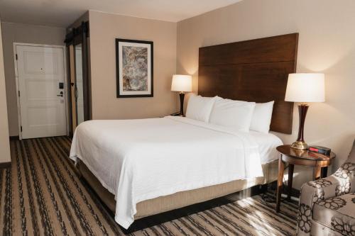 ein Hotelzimmer mit einem großen Bett und einem Stuhl in der Unterkunft Colonial Hotel in Gardner