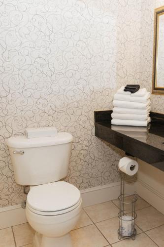 eine weiße Toilette in einem Badezimmer mit Tapete in der Unterkunft Colonial Hotel in Gardner