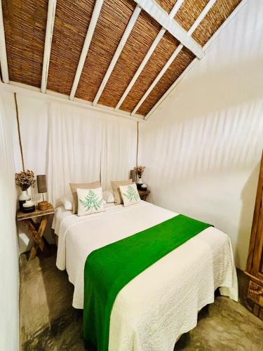 a bedroom with a large white bed with a green blanket at Casas das Piçarras - Alentejo in Piçarra