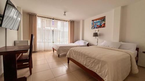 ein Hotelzimmer mit zwei Betten, einem Schreibtisch und einem Fernseher in der Unterkunft Hotel Israel - Lago Agrio in Nueva Loja