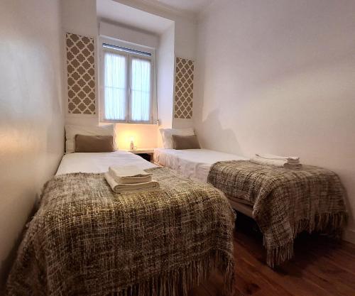 a bedroom with two beds with blankets and a window at Travessa Houses in Lisbon