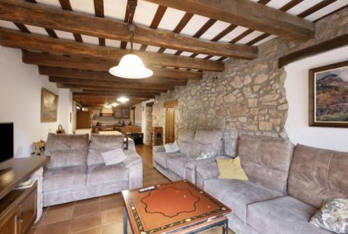 a living room with couches and a stone wall at Cal Vidal in Mura