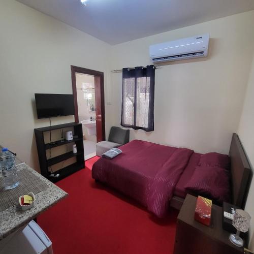 a hotel room with a bed and a television at Cliftin Studio Apartment in Abu Dhabi