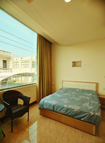 a bedroom with a bed and a chair and a window at 佳家民宿 in Linbian