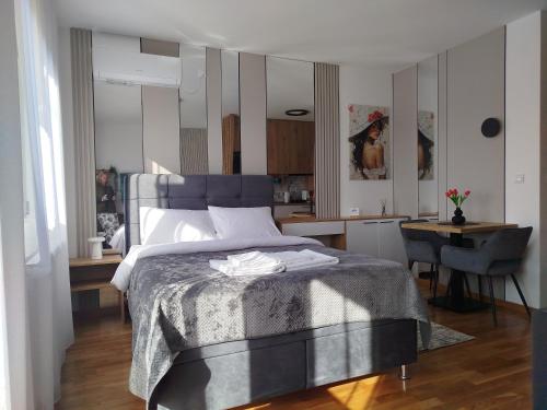 a bedroom with a bed with a table and a kitchen at Studio Sky in Smederevo