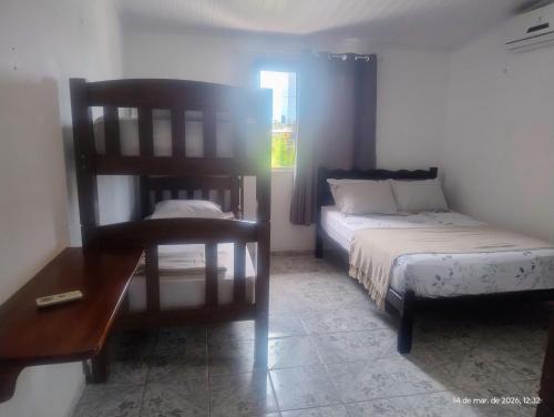a bedroom with a bed and a chair and a table at hostel xamã in Flecheiras