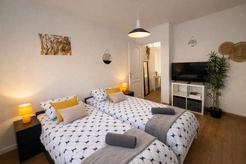 a bedroom with two beds and a flat screen tv at Studio cosy avec parking, tram direct Strasbourg 7 min in Illkirch-Graffenstaden