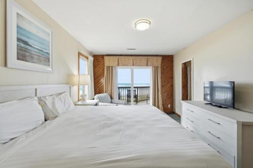 ein Schlafzimmer mit einem weißen Bett und einem Fernseher in der Unterkunft Ocean Pines Resort in Duck