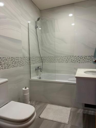 a bathroom with a shower and a toilet and a sink at Ofir Beach Apartment in Fão