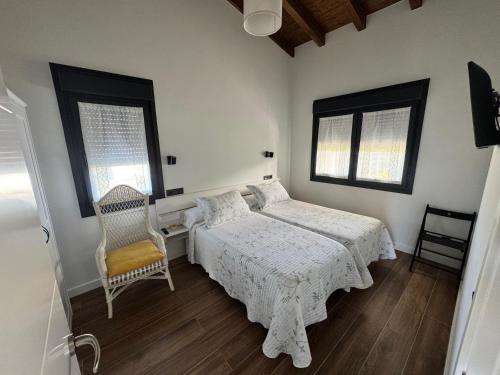 a bedroom with a bed and a chair and two windows at APARTAMENTOS LOS MANZANOS in Ribadesella